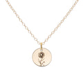 A gold birth flower necklace with an engraved pendant on a delicate cable chain.