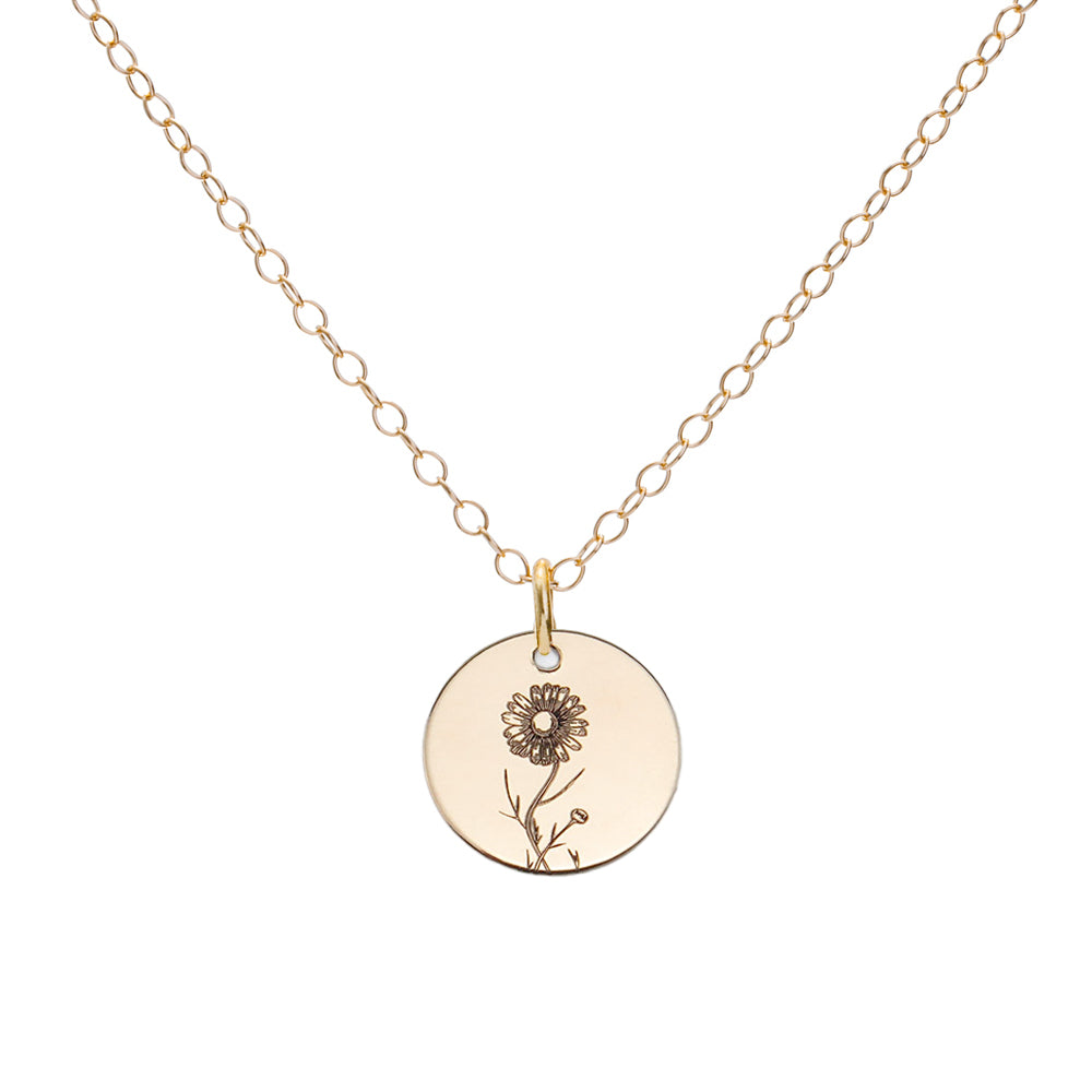 A gold birth flower necklace with an engraved pendant on a delicate cable chain.