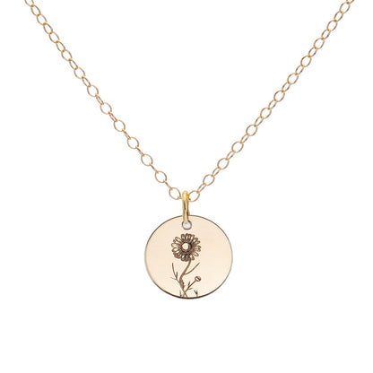 A gold birth flower necklace with an engraved pendant on a delicate cable chain.