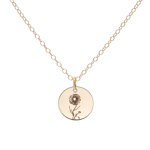A gold birth flower necklace with an engraved pendant on a delicate cable chain.