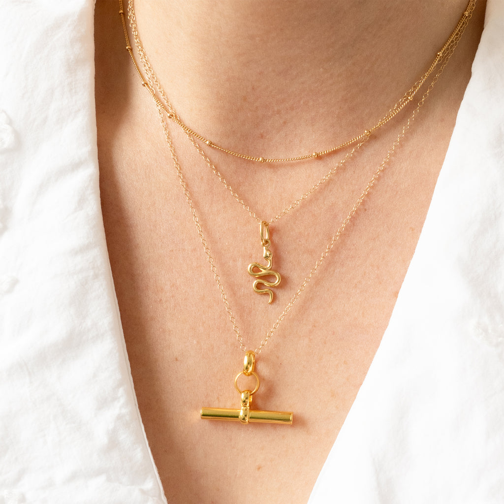 Gold necklaces with charms on a person wearing a white shirt