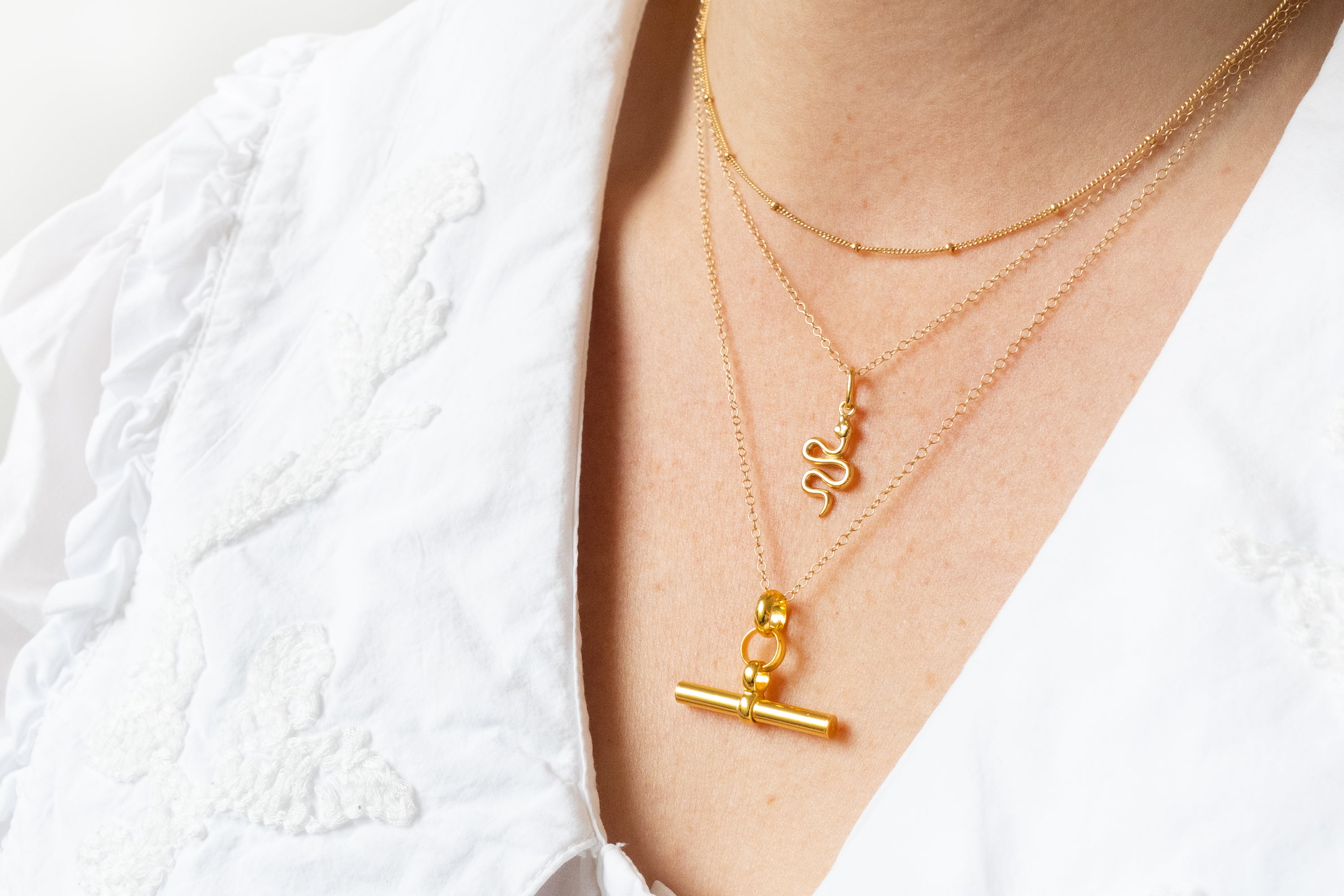 Gold necklaces with unique pendants on a white background