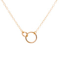 Gold necklace with a circular pendant on a white background