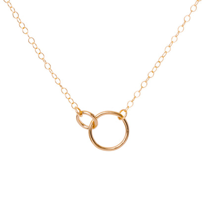 Gold necklace with a circular pendant on a white background